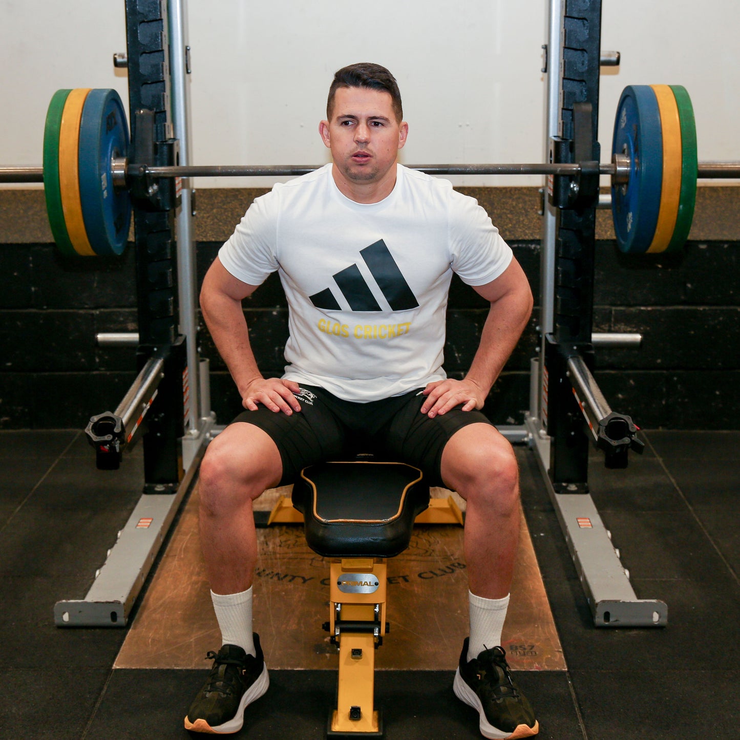 GVB sitting on a weight bench in a gym wearing an Adidas shirt.